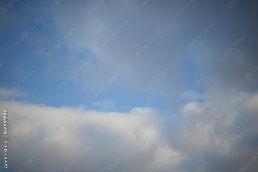 rays of the sun through the cirrus clouds against the blue sky, white rainy clouds blue sky illuminated by the rays of the sun, one small cirrus cloud blurred clouds background