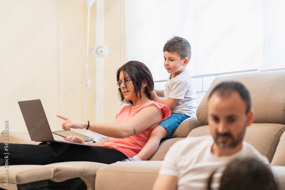 Woman working on laptop during weekend with family Woman working on laptop during weekend with family