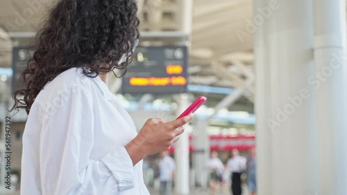 woman with protective face mask in train terminal or airport, using phone, travel during Covid-19 photo