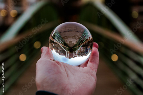 hand holding glass ball on a bridge