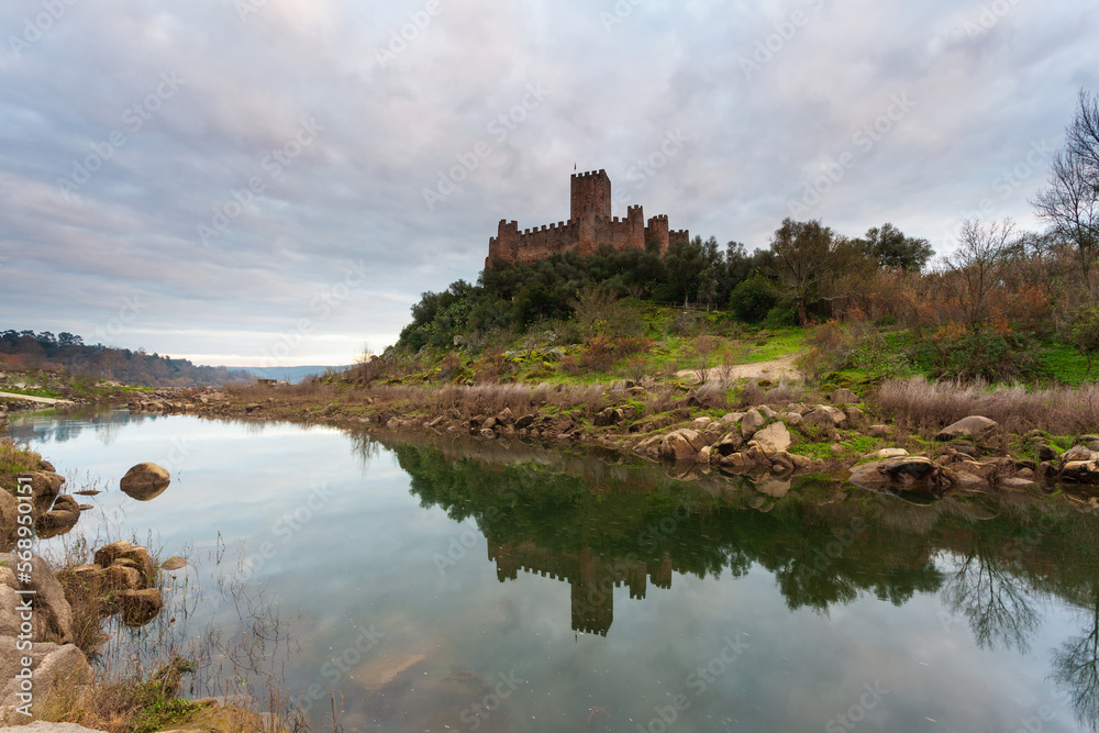 Sunset at Castle Almourol, river Tagus in Portugal. Amazing landscape at sunset with the castle walls under red cloud sky. Beautiful Landmark is a vacation travel destination.