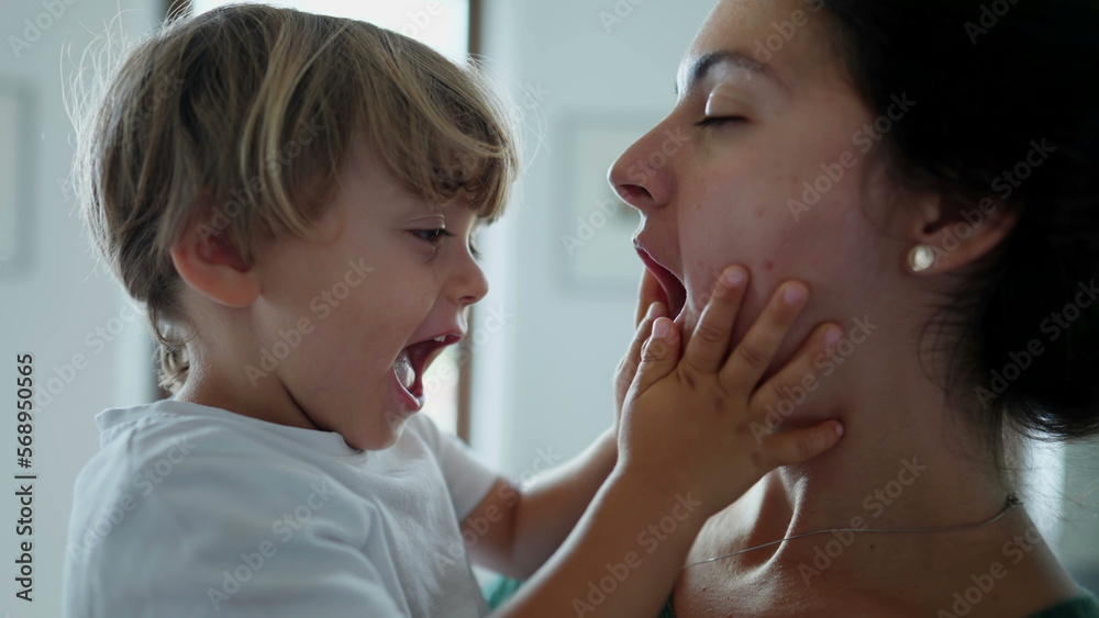 Mother holding child in arms kissing and embracing kid. Candid mom showing love affection to young boy. Authentic real life motherhood relationship Mother holding child in arms kissing and embracing kid. Candid mom showing love affection to young boy. Authentic real life motherhood relationship