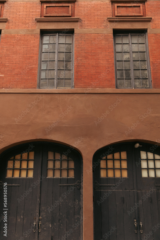 Naklejka premium Wooden doors on facade of brick building on street in New York City.