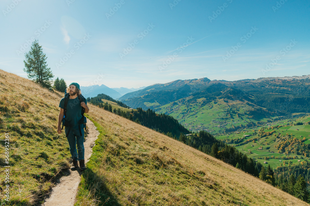 Man hiking on trail in Swiss Alps in autumn Man hiking on trail in Swiss Alps in autumn