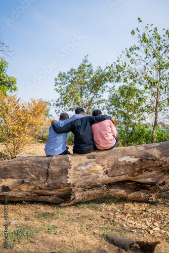 Three queer masculine women share a hug at the park