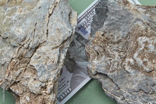 100 dollar bill crushed by two large stones. photo