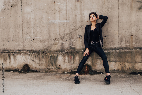 Pretty woman posing near gray wall. Girl dressed casual outfits with red lips. Fashion, make up, hairstyle 