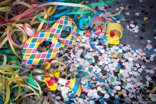 Venetian harlequin style mask with confetti and trumpets around on a marble table
