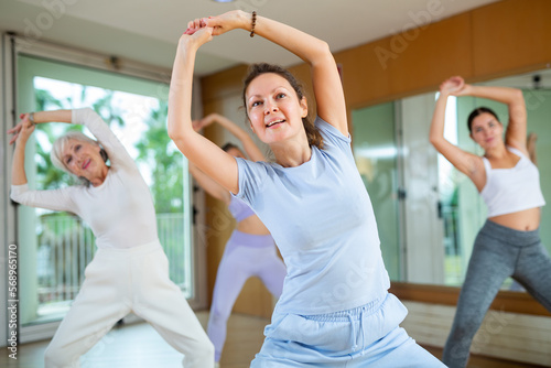 Practiced middle-aged woman engaging in aerobics in dance studio during workout session. Women training dance in hall