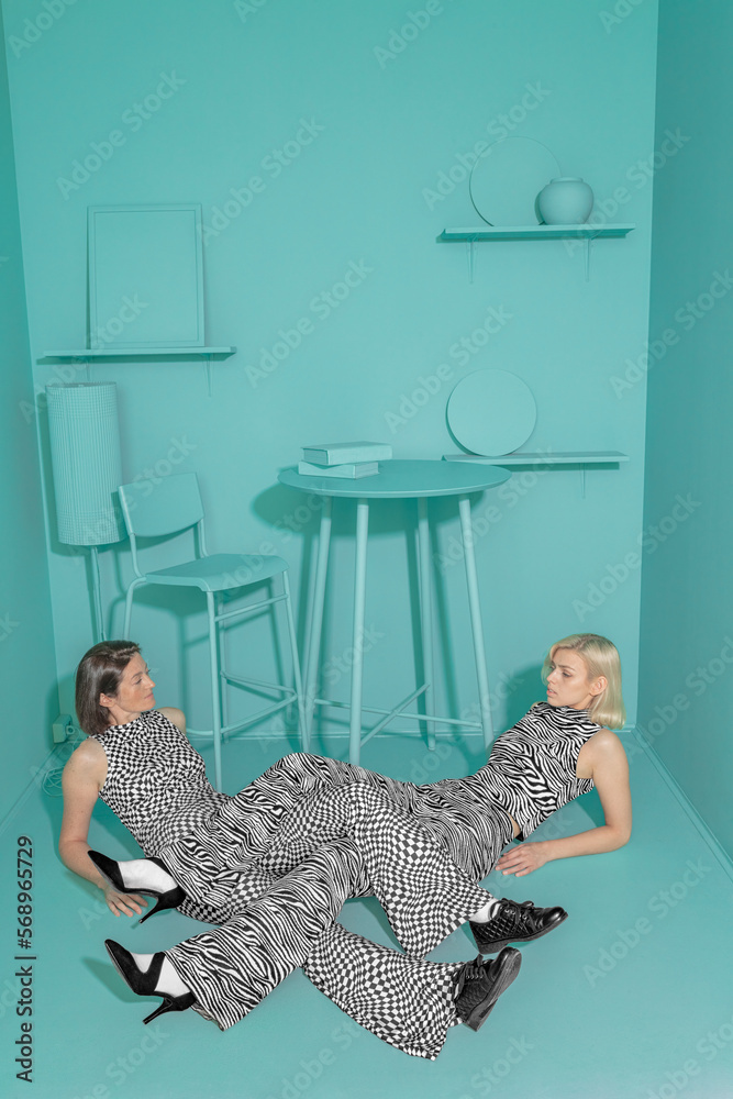 conceptual portrait of two girls in an art space with intertwined legs