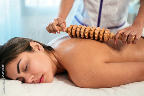 Masseuse massaging back with maderotherapy massage roller photo