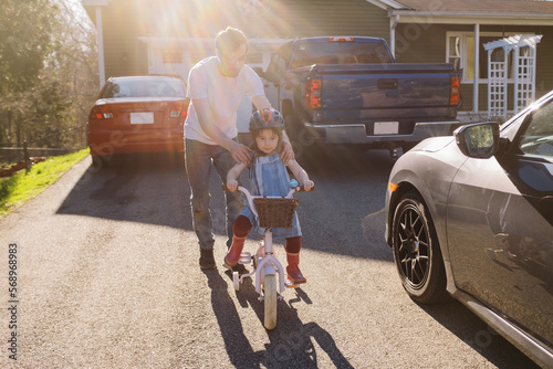 Dad helping his happy daughter to learn to ride a bicycle  photo