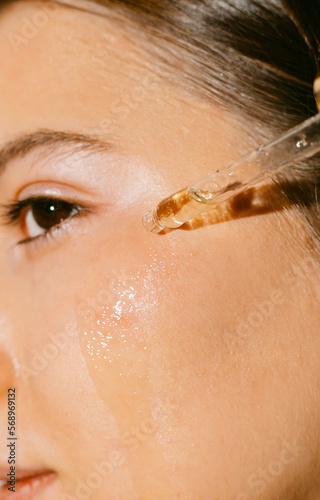 A young woman applying a face and body oil 