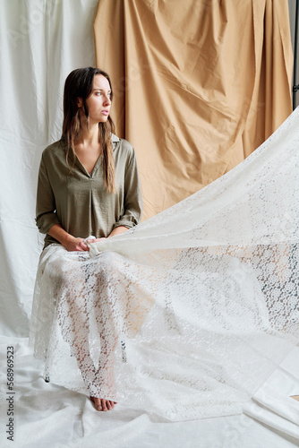 Woman sitting near the curtains in the studio. photo