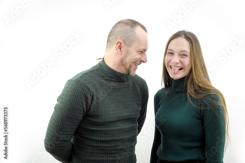 girl trolls man a young girl with long hair shows her tongue to him father and young daughter smile joy fun good mood couple in dark green stockings smiles the joke is perceived