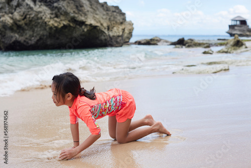 Asian girl crawling and playing on the beautiful seaside beach photo