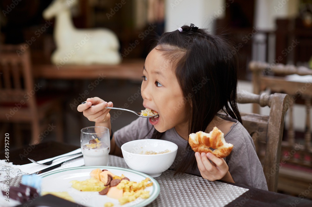 Asian little girl, eating breakfast in hotel Asian little girl, eating breakfast in hotel