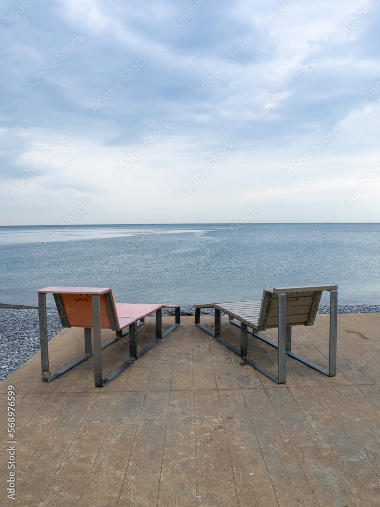 Benches for lying by the sea. Sun loungers in the park against the background of the sea. Benches for lying by the sea. Sun loungers in the park against the background of the sea.