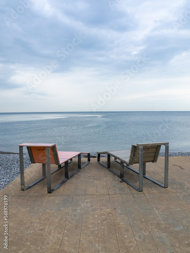 Benches for lying by the sea. Sun loungers in the park against the background of the sea. © Aleksandr