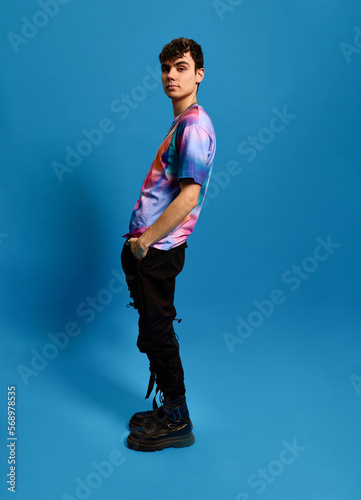 Confident cool guy standing in blue studio