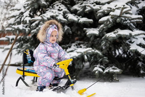 Baby girl play outdoors in snow, enjoy a sleigh ride. Child sledding. Toddler kid riding a sledge. Sled in winter.