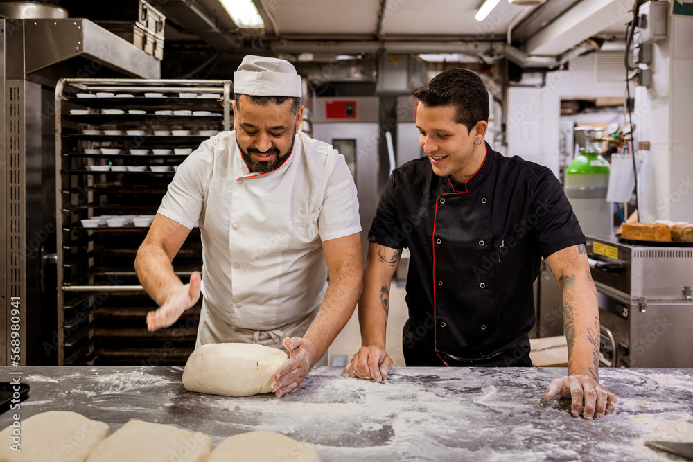 © VICTOR TORRES/Stocksy - Baker teaching colleague to make dough