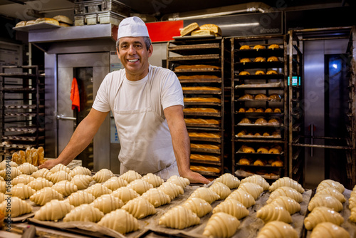 Happy baker behind table with croissants photo