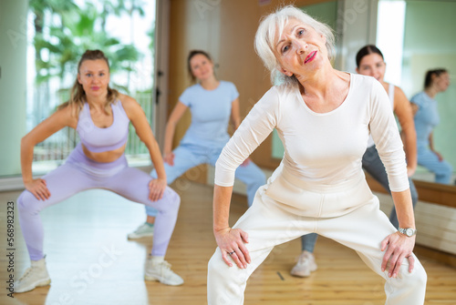 Practiced old-aged woman engaging in aerobics in dance studio during workout session. Women training dance in hall