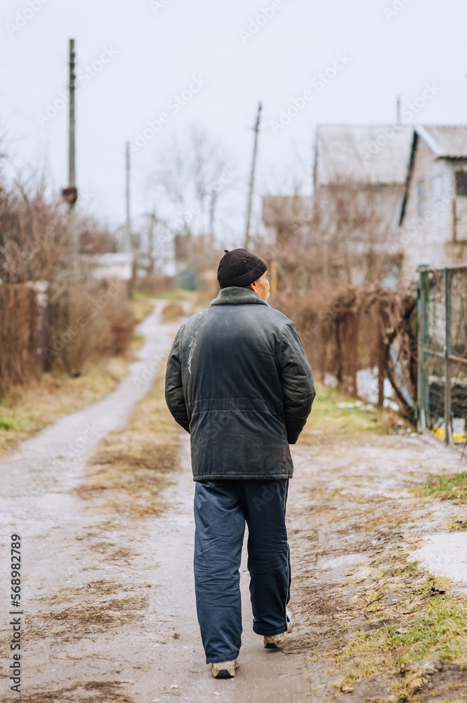 A lone man in dirty torn clothes, a beggar tramp, an old bum walks on the street in search of food. Photography, concept, lifestyle.