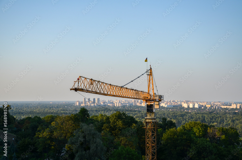 Tower crane on the background of Dnipro river and left bank of Kyiv city. New buildings architecture and industry construction