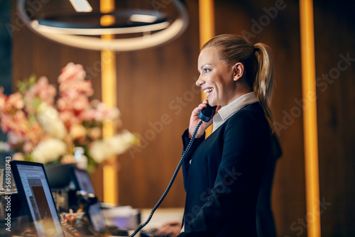 Fotografie A happy receptionist is answering calls at reception.