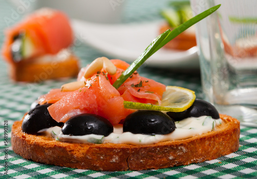Tasty canape with salmon and olives with white sauce