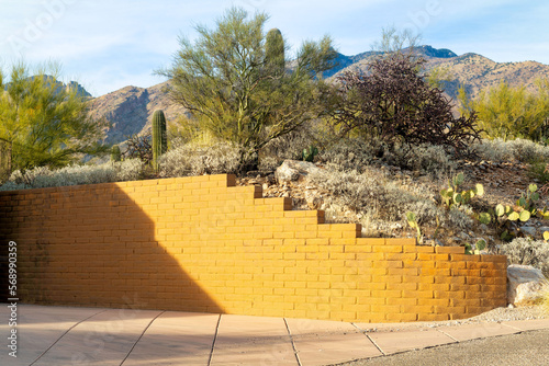 Yellow brick retaining wall wrapping around small hill in front yard of house or home in a desert rural community area photo