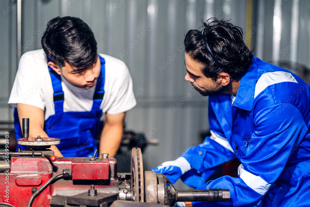 Professional two labor machanic engineer technician worker industrial man wearing blue safety uniform working control with heavy machine in manufacturing factory production line.business industry Professional two labor machanic engineer technician worker industrial man wearing blue safety uniform working control with heavy machine in manufacturing factory production line.business industry