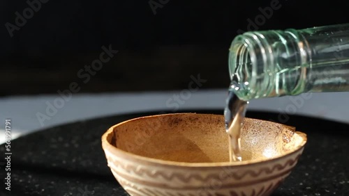 zoom in of person serving shot of mezcal in jicara bowl. silver tequila photo