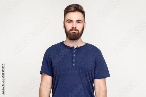 Wallpaper Mural Portrait of serious handsome man with beard wearing dark blue T-shirt standing with hands down and looking at camera with strict expression. Indoor shot isolated on gray background. Torontodigital.ca