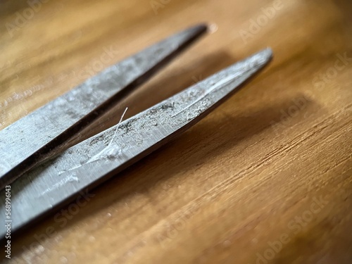 Selective focus view of scissor with dirty blade on wooden background. Macro photography.