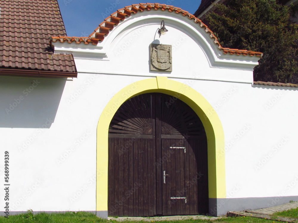 Village still life - an ancient wooden gate with an arc in white wall, entrance in courtyard Village still life - an ancient wooden gate with an arc in white wall, entrance in courtyard