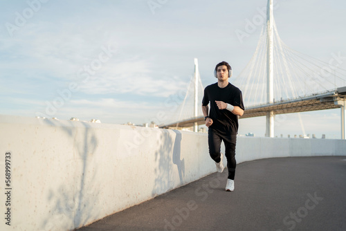 A sporty lifestyle in comfortable clothes. . A man fitness running outdoors listening to music for sports with headphones.