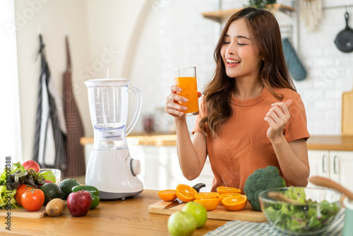 Portrait of beauty body slim healthy asian woman drinking glass of juice and orange.young girl preparing cooking healthy drink with fresh orange juice in kitchen at home.Diet concept.healthy drink