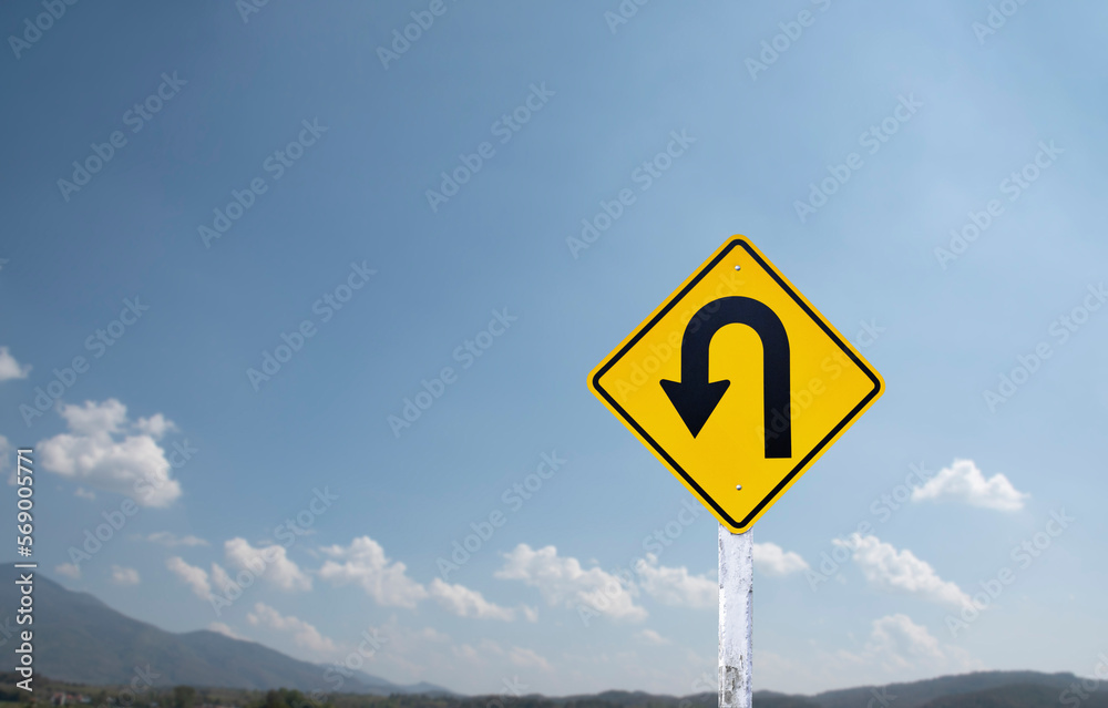 Traffic sign: left U-turn sign on cement pole beside the rural road with white cloudy bluesky background, copy space. Traffic sign: left U-turn sign on cement pole beside the rural road with white cloudy bluesky background, copy space.