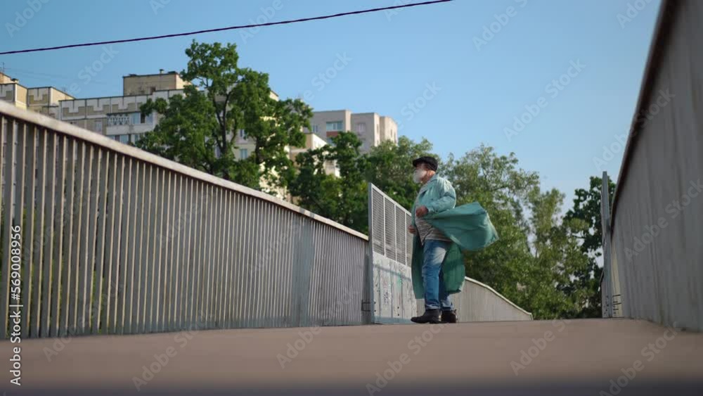 Wide shot cheerful senior bearded man dancing in slow motion on urban city bridge on sunny spring summer day. Portrait of joyful happy relaxed Caucasian retiree having fun outdoors Wide shot cheerful senior bearded man dancing in slow motion on urban city bridge on sunny spring summer day. Portrait of joyful happy relaxed Caucasian retiree having fun outdoors