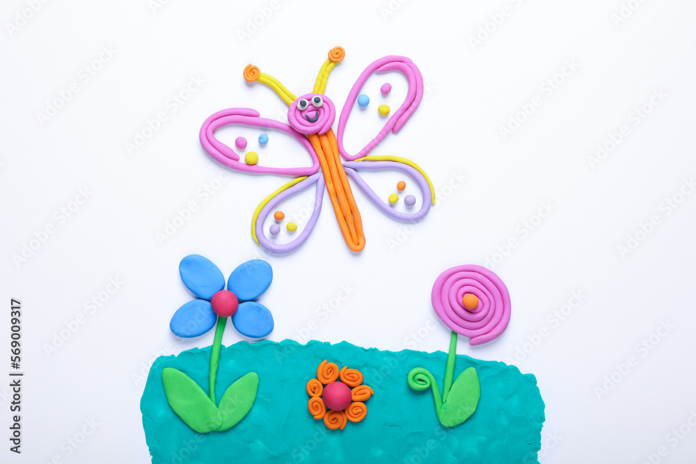 Butterfly and flowers made of plasticine on white background, top view
