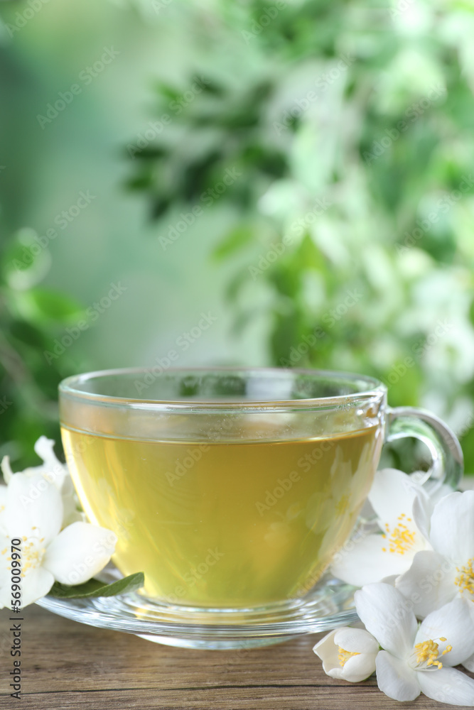 Cup of tea and fresh jasmine flowers on wooden table. Space for text Cup of tea and fresh jasmine flowers on wooden table. Space for text