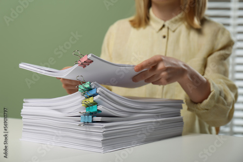 Woman stacking documents at white table in office, closeup