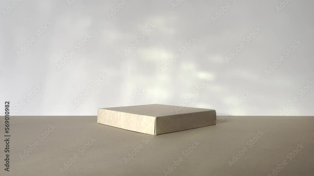 Square podium with reflections of the sun. Beige background with palm tree shadow. Product promotion. Front view, studio shot.