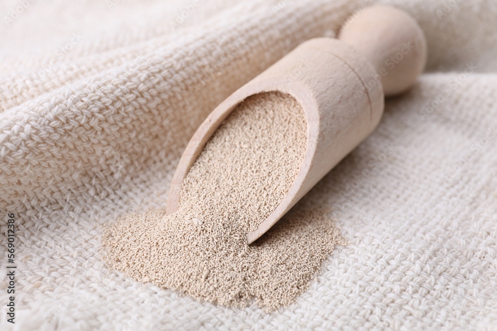 Wooden scoop with active dry yeast on cloth, closeup Wooden scoop with active dry yeast on cloth, closeup