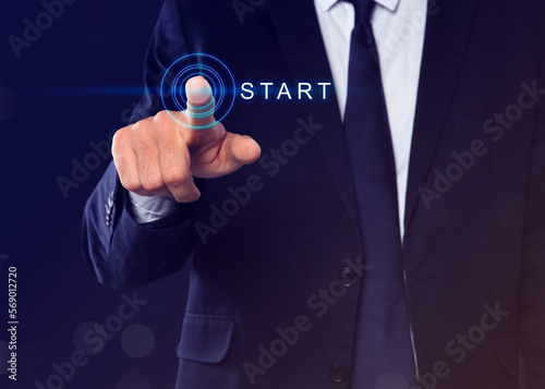 Man pressing start button on virtual screen against dark blue background, closeup