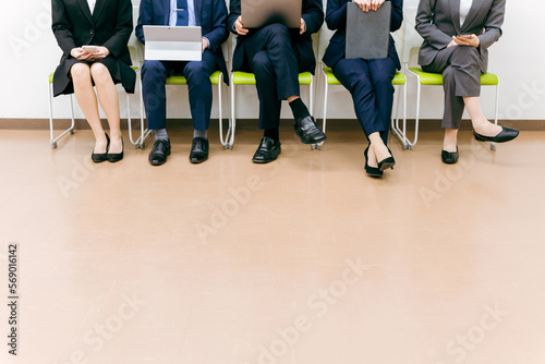会社でパソコン・スマホ・タブレットを使うスーツ姿の会社員（アジア人・男女・5人）