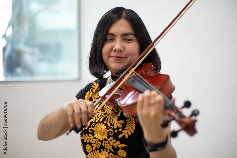 good looking hispanic violinist girl playing violin smiling using traditional dress. portrait of a young woman latin viloinist musician smiling